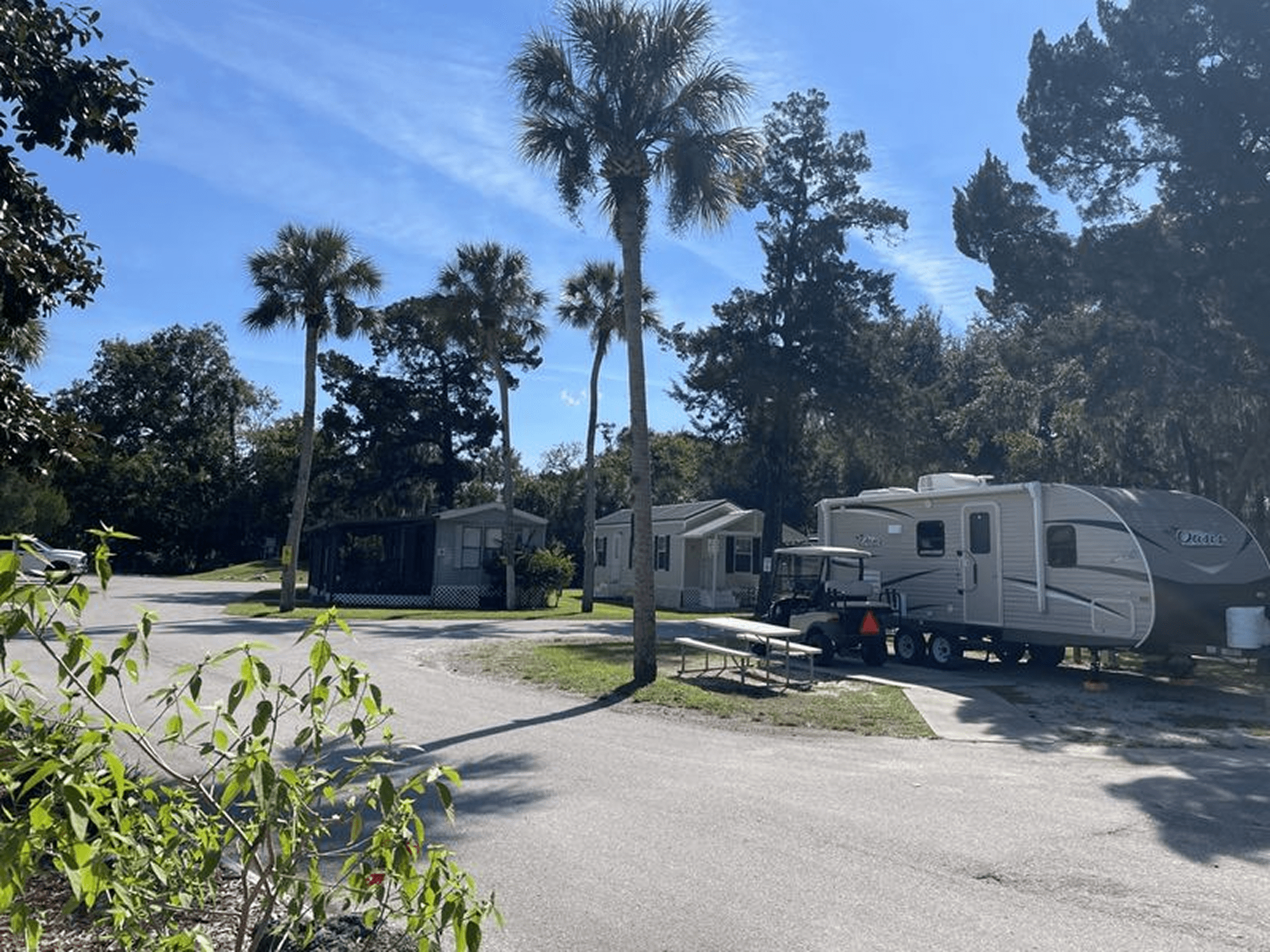 Trailer and cabins in lush campground setting.