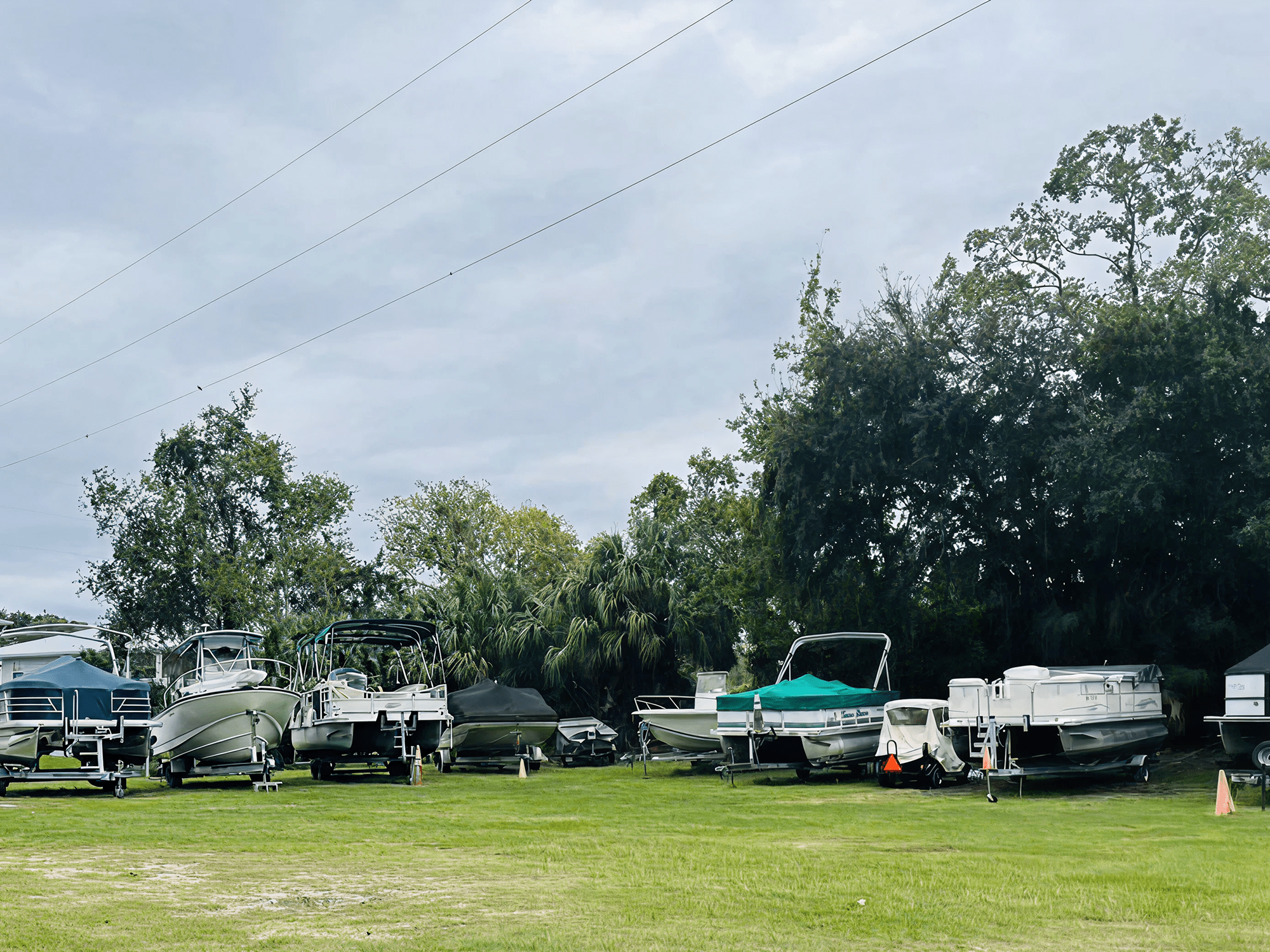 Boats parked on grass under cloudy sky.