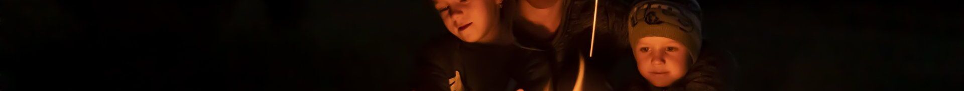 Youngsters' faces lit by campfire flames